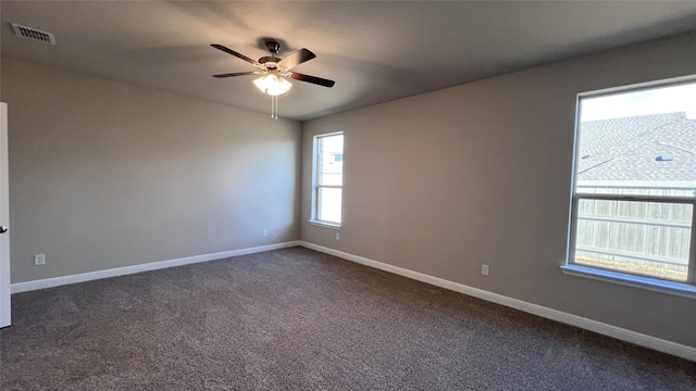 empty room with ceiling fan and dark colored carpet