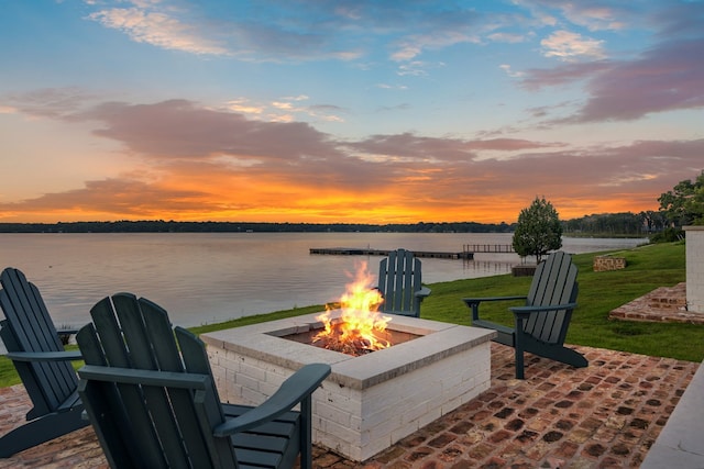 patio terrace at dusk featuring a water view and a fire pit