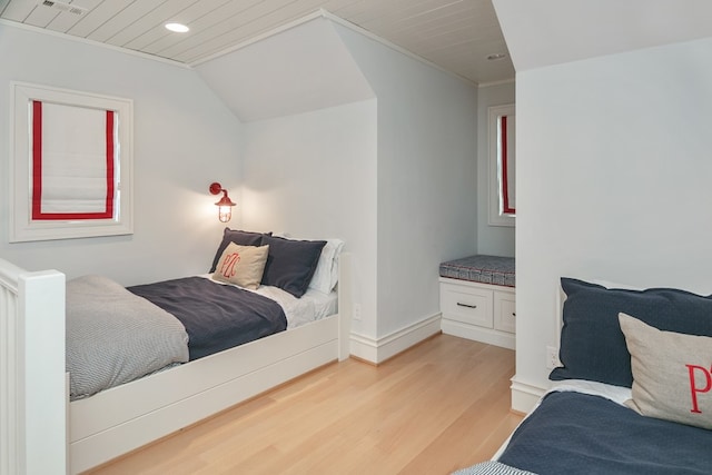 bedroom with crown molding, lofted ceiling, and light hardwood / wood-style flooring