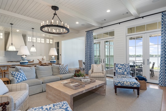 living room featuring beamed ceiling, a water view, a chandelier, and french doors