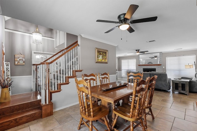 tiled dining space featuring crown molding, a fireplace, and a chandelier