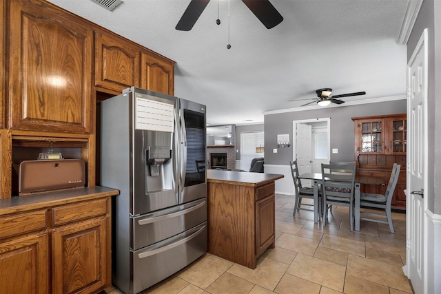 kitchen featuring stainless steel fridge with ice dispenser, a fireplace, ceiling fan, and light tile patterned flooring