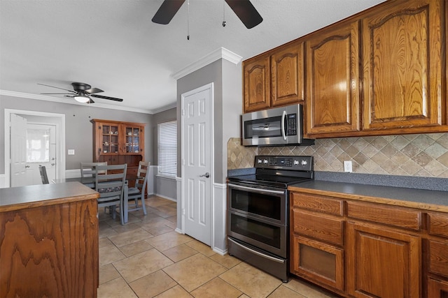 kitchen featuring stainless steel appliances, crown molding, ceiling fan, and decorative backsplash