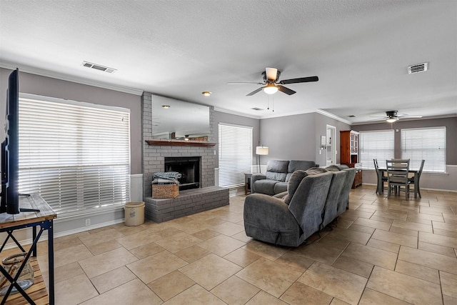 tiled living room featuring crown molding, ceiling fan, a textured ceiling, and a fireplace