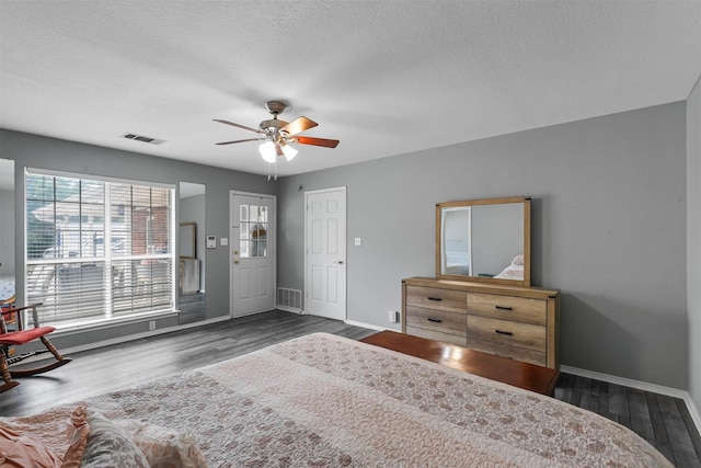 bedroom featuring ceiling fan, dark hardwood / wood-style flooring, and a textured ceiling