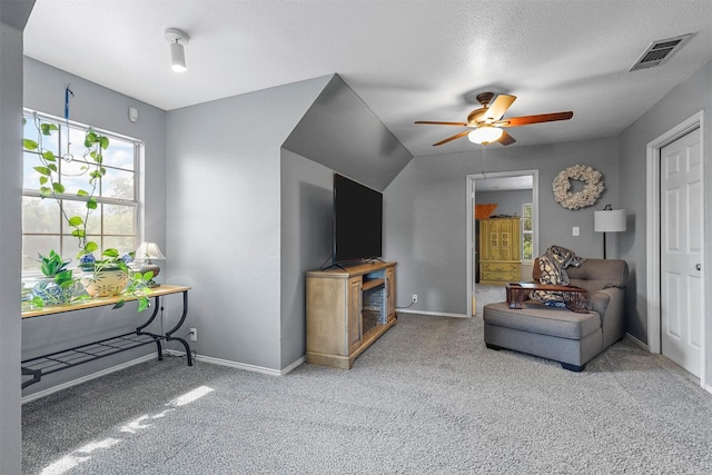 living room with ceiling fan, light colored carpet, and a textured ceiling