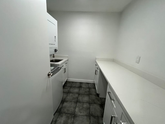 kitchen featuring white cabinetry and stacked washer / dryer