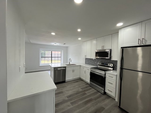 kitchen featuring sink, appliances with stainless steel finishes, white cabinetry, backsplash, and kitchen peninsula