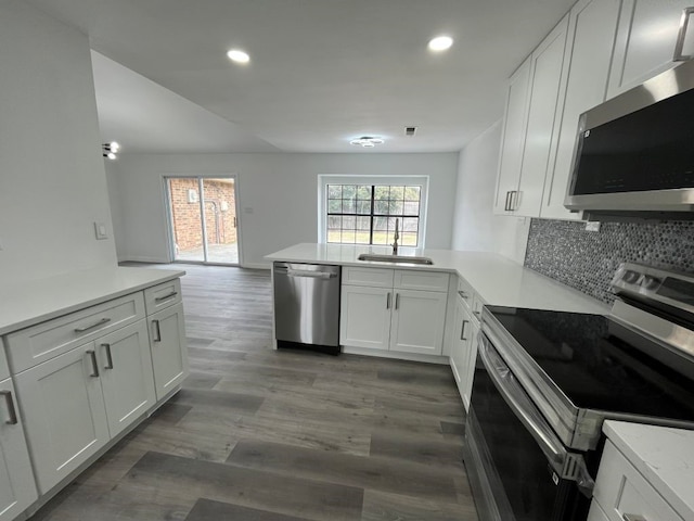 kitchen featuring sink, white cabinetry, dark hardwood / wood-style flooring, kitchen peninsula, and stainless steel appliances