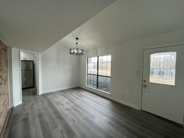 entrance foyer with hardwood / wood-style flooring, lofted ceiling, and an inviting chandelier