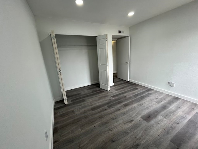 unfurnished bedroom featuring dark wood-type flooring and a closet