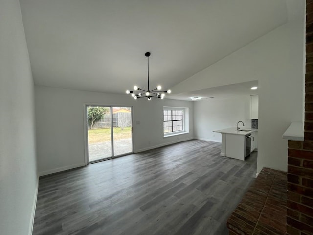 unfurnished dining area featuring an inviting chandelier, high vaulted ceiling, dark hardwood / wood-style flooring, and sink