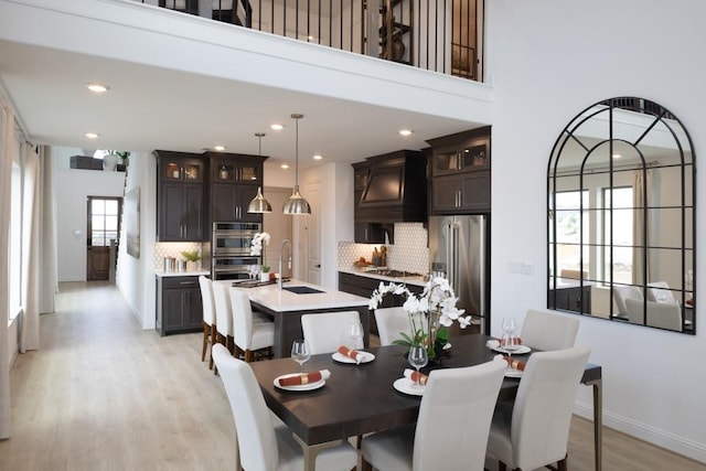 dining space with sink, light hardwood / wood-style flooring, and a high ceiling