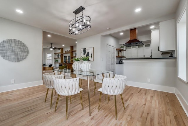 dining area with ceiling fan with notable chandelier and light hardwood / wood-style floors