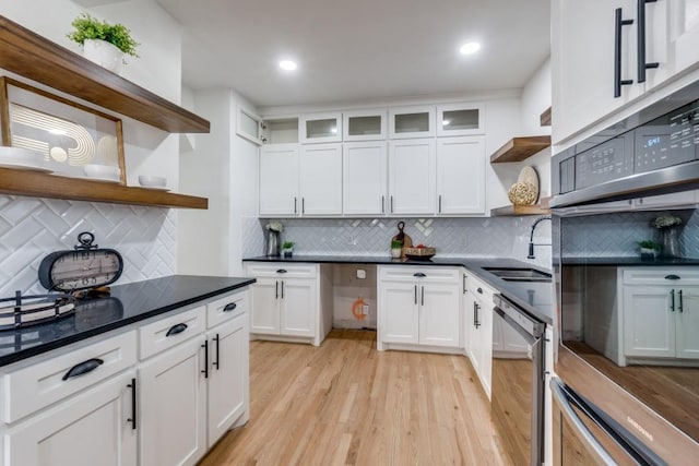 kitchen with sink, light wood-type flooring, white cabinets, and appliances with stainless steel finishes