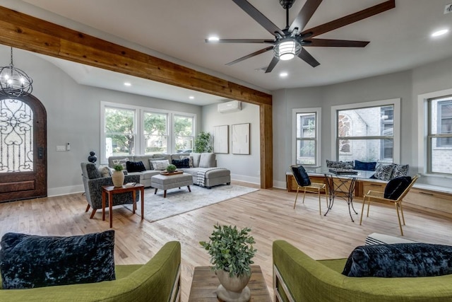 living room featuring beamed ceiling, ceiling fan with notable chandelier, a wall mounted air conditioner, and light hardwood / wood-style floors