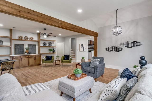 living room featuring beam ceiling, light hardwood / wood-style flooring, and ceiling fan with notable chandelier