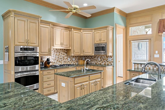 kitchen with sink, ornamental molding, stainless steel appliances, and a center island with sink