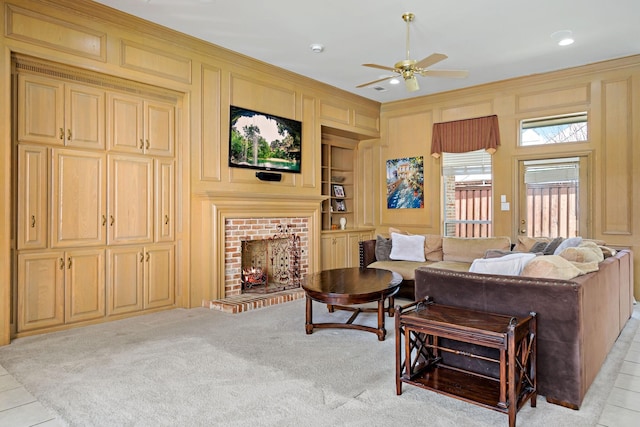 living room featuring a fireplace, ceiling fan, crown molding, light carpet, and built in shelves