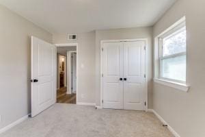 unfurnished bedroom featuring light carpet and a closet