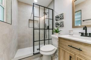 bathroom featuring vanity, toilet, and a tile shower