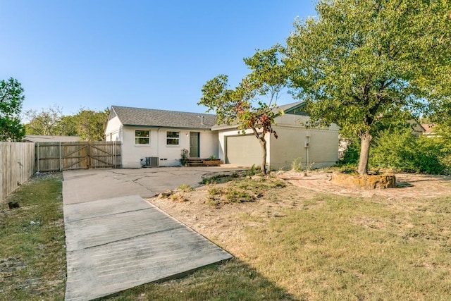 rear view of house featuring cooling unit, a garage, and a yard