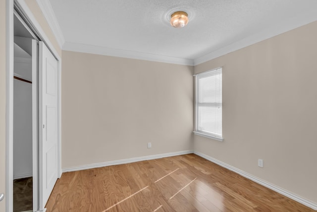 unfurnished bedroom featuring a closet, ornamental molding, light hardwood / wood-style flooring, and a textured ceiling