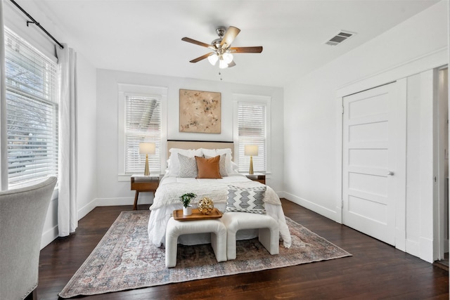 bedroom featuring ceiling fan, dark hardwood / wood-style flooring, and multiple windows