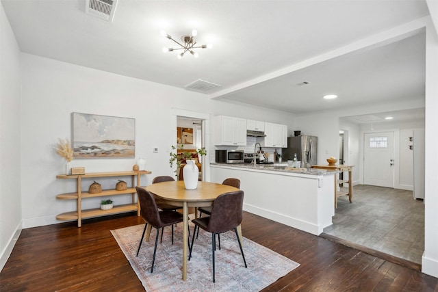 dining area featuring dark hardwood / wood-style flooring, sink, and an inviting chandelier