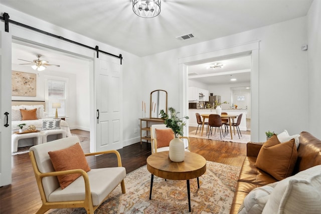 living room featuring a barn door, hardwood / wood-style floors, and ceiling fan