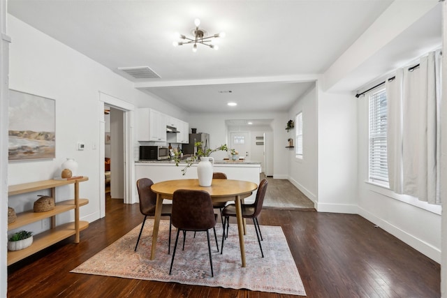 dining area with dark hardwood / wood-style flooring and an inviting chandelier