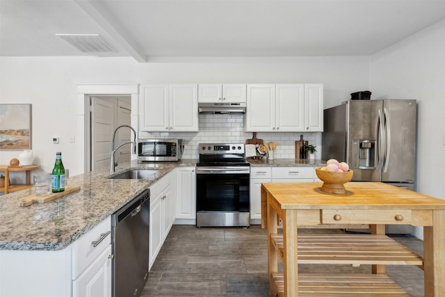 kitchen featuring appliances with stainless steel finishes, tasteful backsplash, white cabinetry, sink, and light stone counters