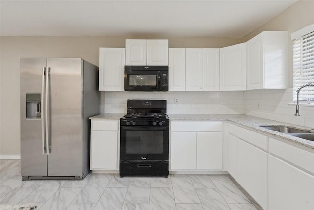 kitchen featuring sink, light stone counters, black appliances, white cabinets, and decorative backsplash