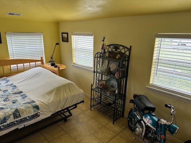 bedroom featuring a textured ceiling and light tile patterned floors