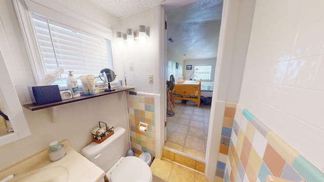 bathroom featuring vanity, tile walls, a textured ceiling, and toilet