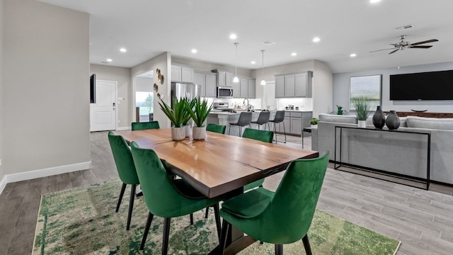 dining area with ceiling fan, sink, and light hardwood / wood-style floors