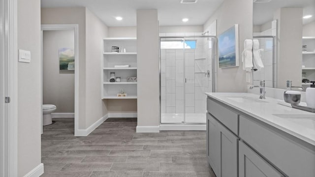 bathroom featuring hardwood / wood-style flooring, vanity, toilet, and a shower with door