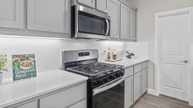 kitchen featuring gray cabinetry, backsplash, light hardwood / wood-style floors, and appliances with stainless steel finishes