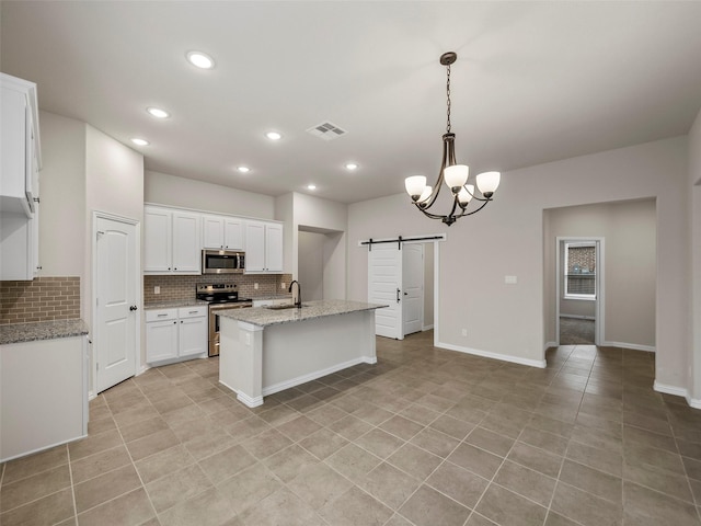 kitchen with white cabinetry, sink, a kitchen island with sink, stainless steel appliances, and a barn door