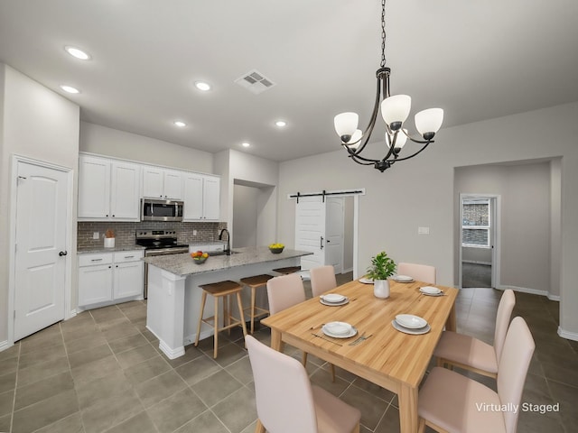 tiled dining space with an inviting chandelier, a barn door, and sink