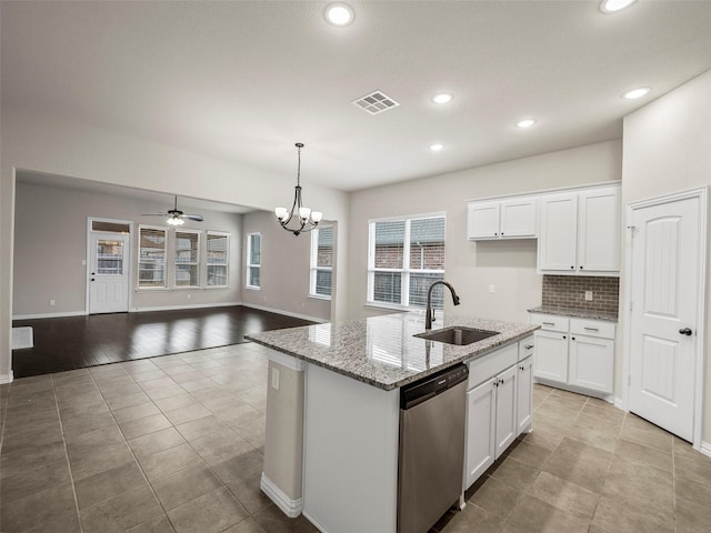 kitchen featuring dishwasher, sink, white cabinets, light stone countertops, and a center island with sink