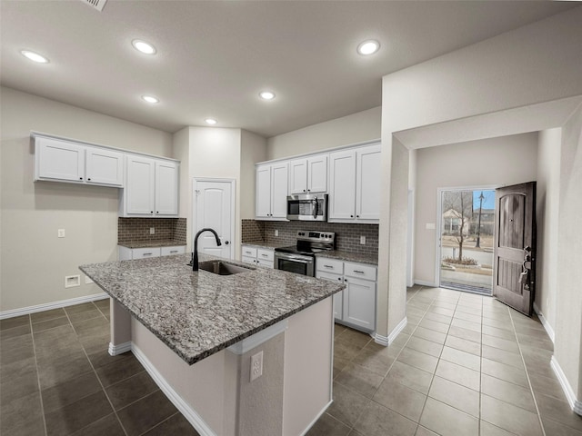 kitchen with an island with sink, stainless steel appliances, sink, and white cabinets