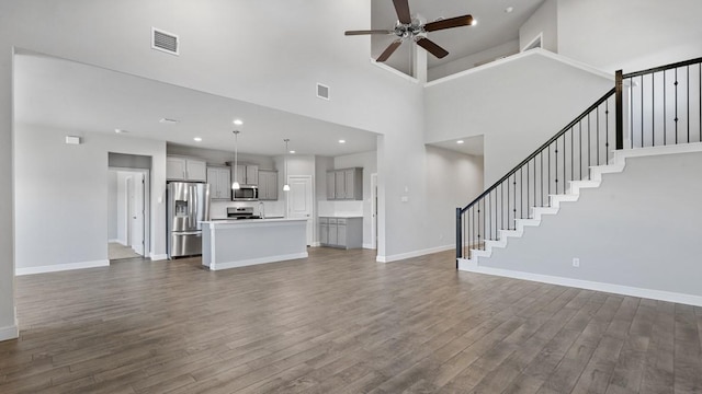 unfurnished living room featuring ceiling fan, a towering ceiling, and dark hardwood / wood-style flooring