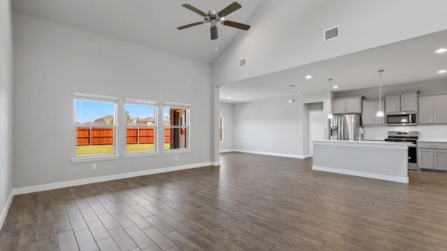 unfurnished living room featuring dark hardwood / wood-style flooring, high vaulted ceiling, and ceiling fan