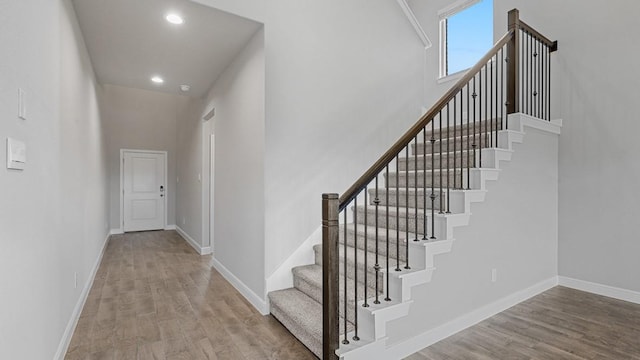 stairs featuring a towering ceiling and hardwood / wood-style floors