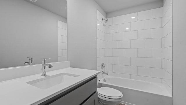 full bathroom with tiled shower / bath, vanity, and toilet