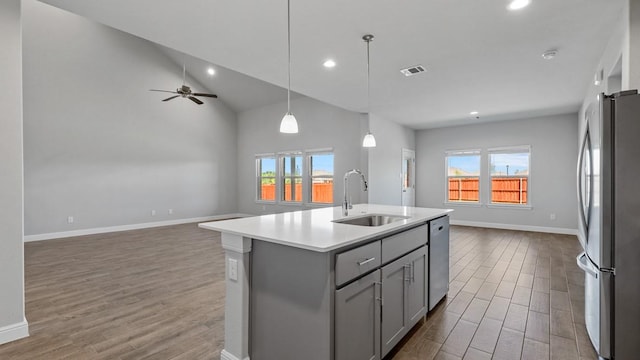 kitchen featuring gray cabinets, appliances with stainless steel finishes, pendant lighting, sink, and a center island with sink