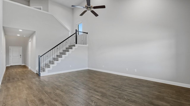 unfurnished living room featuring hardwood / wood-style floors, ceiling fan, and a high ceiling