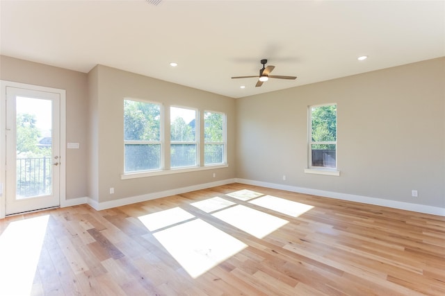 empty room featuring a healthy amount of sunlight, ceiling fan, and light hardwood / wood-style flooring