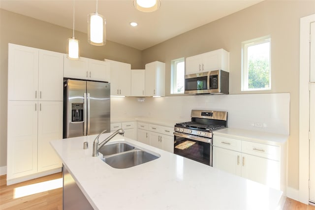 kitchen featuring white cabinetry, sink, decorative light fixtures, and stainless steel appliances